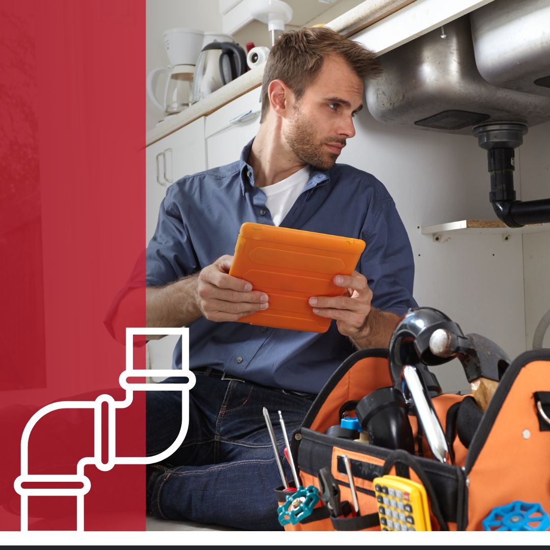 plumber looking under sink, holding tablet