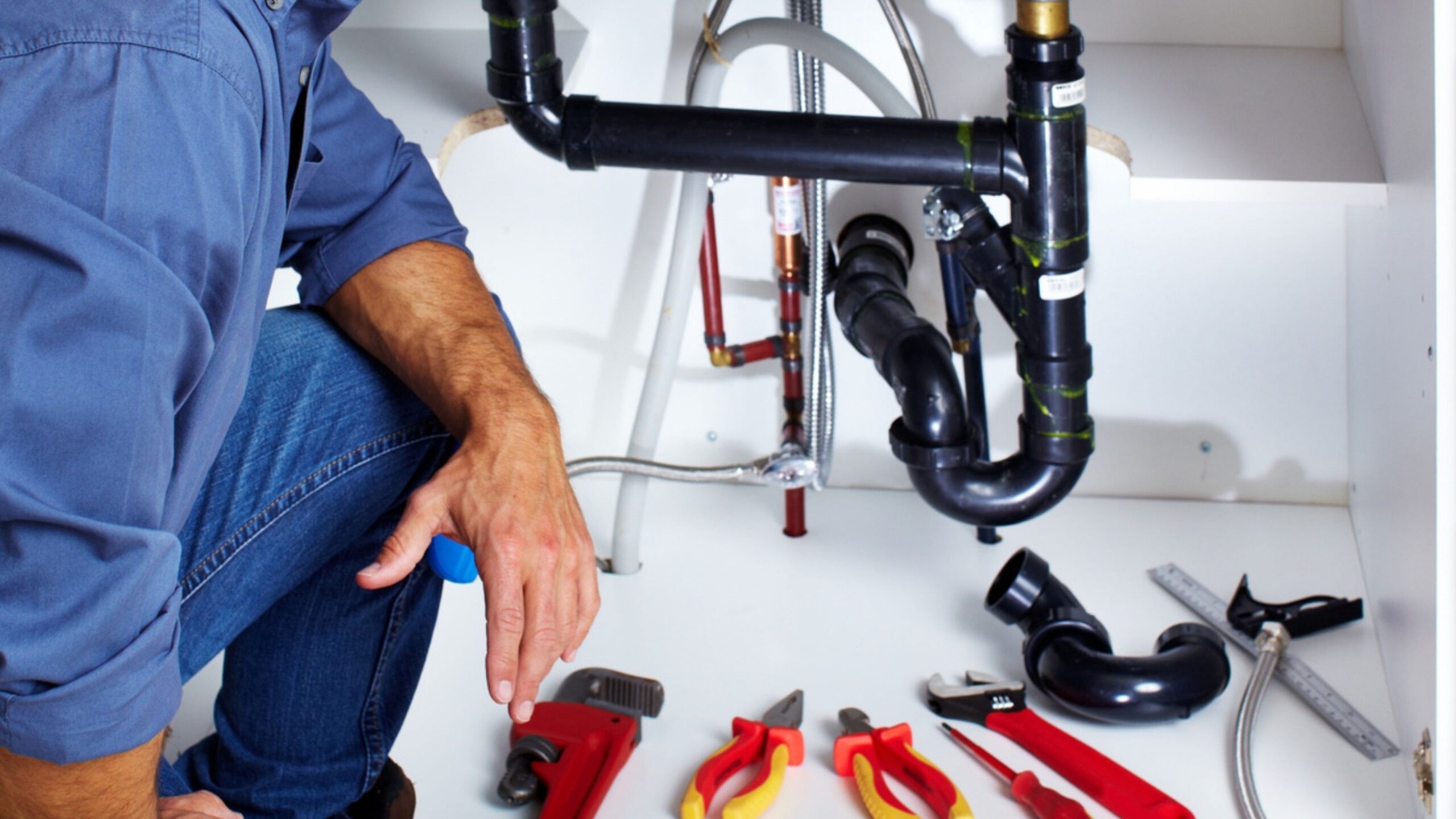 Plumber with his tools under the sink