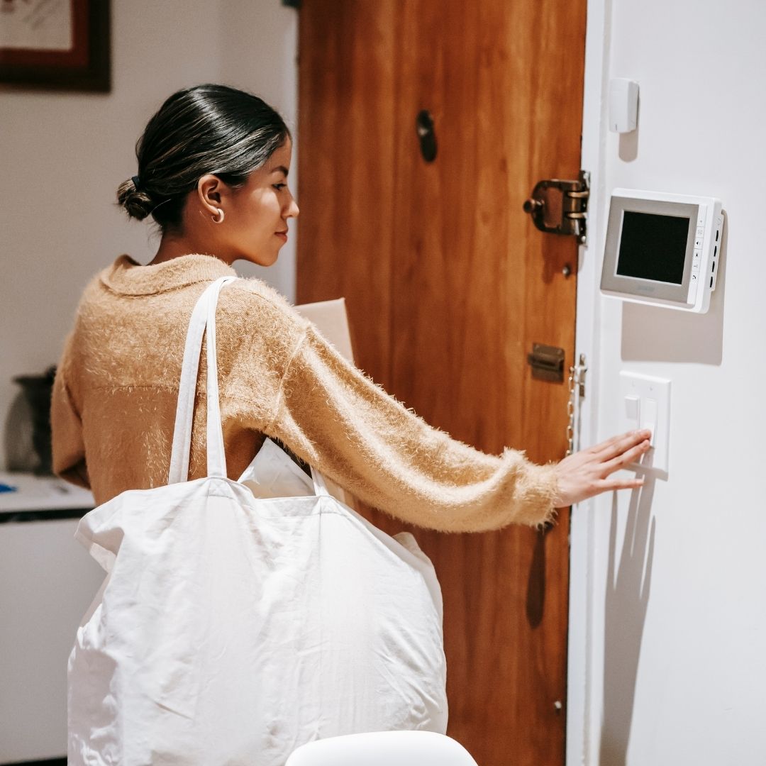 woman adjusting thermostat as she leaves